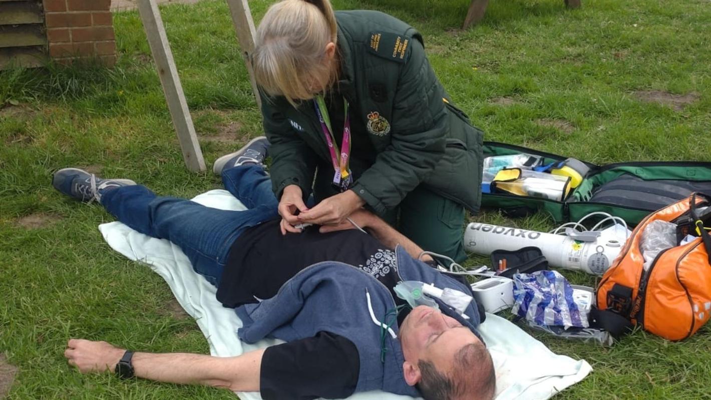 CFR with an actor pretending to be a patient, laying on the floor being attended to.